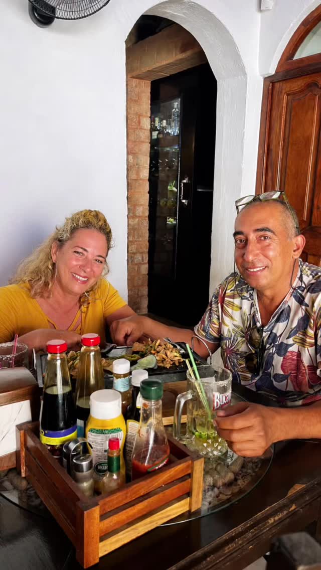 Pareja de clientes posando bajo el arco blanco colonial de Churros D'Andux, con puerta de madera y ambiente cálido del interior